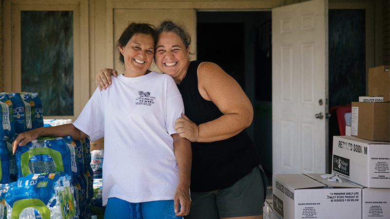 Photo of two smiling women with boxed supplies